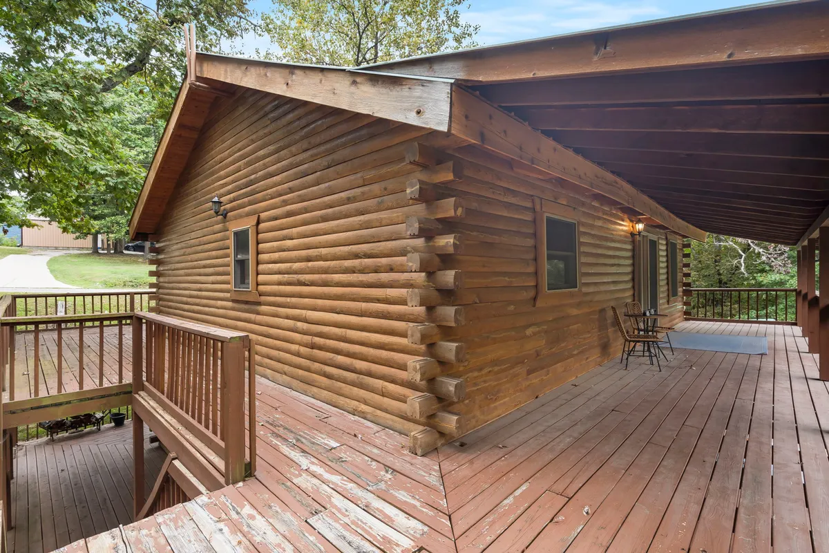 A cozy log cabin exterior with a wooden deck, featuring two chairs perfectly positioned for enjoying sunrise or stargazing. The surrounding greenery enhances the feeling of privacy and connection to nature, reinforcing the allure of returning to your own space after a day of exploration.