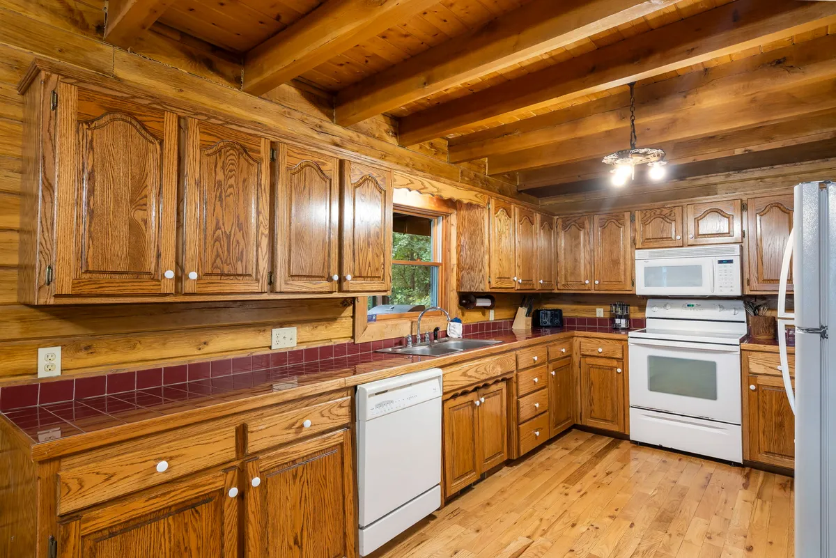 A well-equipped kitchen with wooden cabinetry, modern appliances, a bright window, and an adjoining dining area. The space feels practical yet homey, inviting both casual breakfasts and festive group dinners.